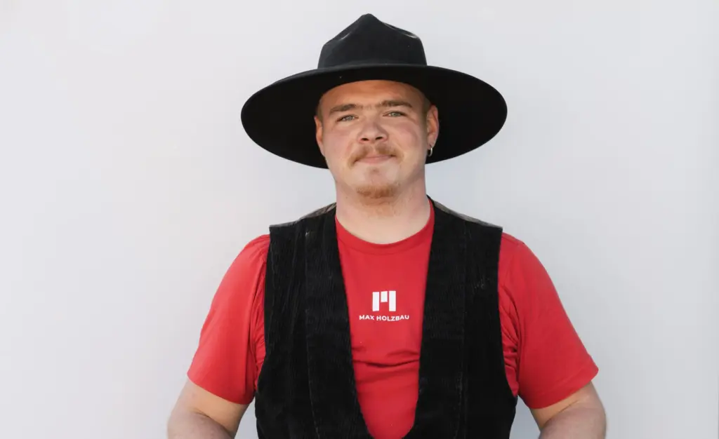 Jobs 4 Mitarbeiter in Zimmererkluft vor grauer Wand