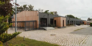 Mischfassade eines Bürogebäudes in Holzbauweise mitten in Berlin mit Fahrradständern und großen Fenstern