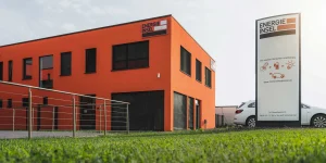 Orangefarbenes Bürogebäude der Energieinsel mit Putzfassade und Jalousien